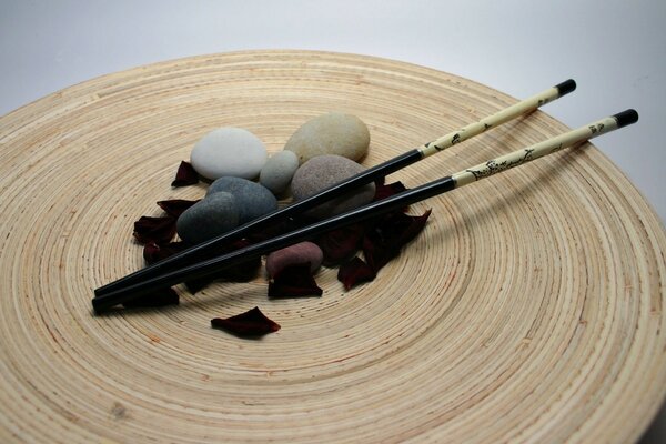 Japanische Stäbchen mit Steinen und Rosenblättern