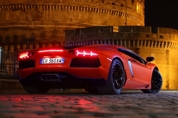 Lamborghini aventador lp 700-4 rouge sur fond de pavés et de murs de briques