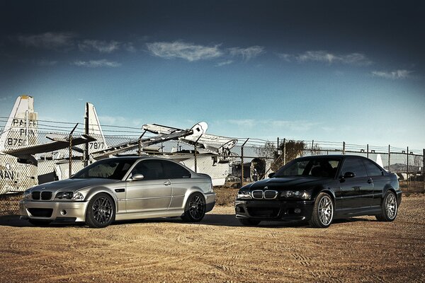 Two BMWs standing against the background of airplanes