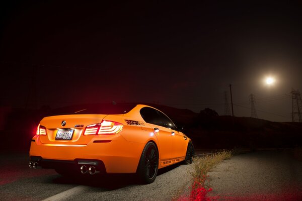 Faros en una noche de BMW naranja en la carretera