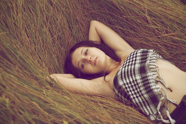 The girl is resting on the hay covered with an Arafat