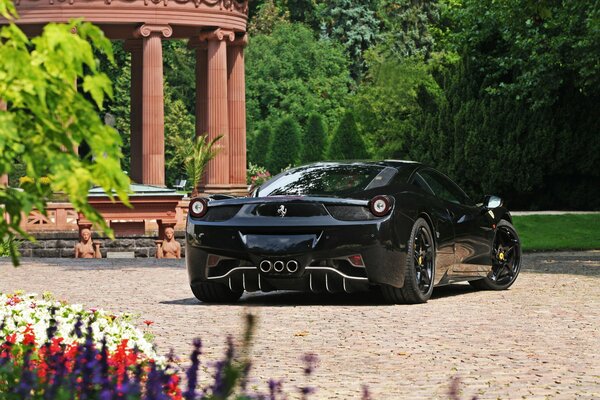 Une voiture Ferrari noire se trouve dans le jardin