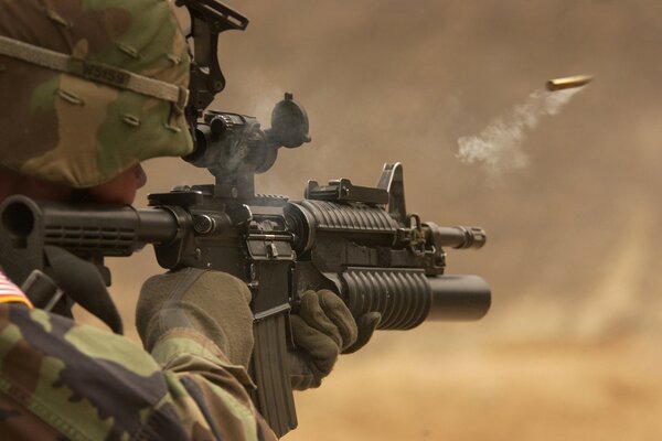 The image of a soldier with a gun in his hands and a flying cartridge case