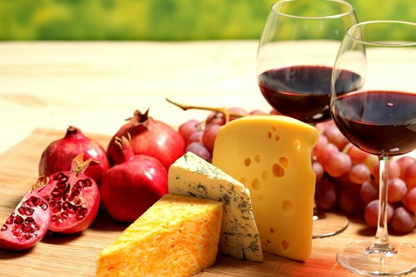 Two glasses of wine with cheese, grapes and pomegranate