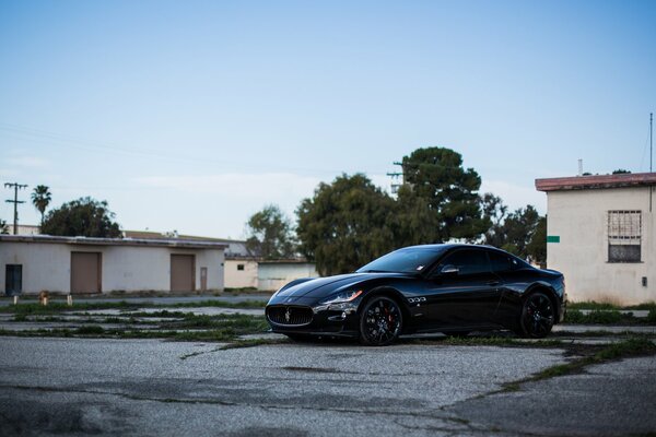 Somewhere behind the houses there is a black maserati on black disks, a gorgeous side view