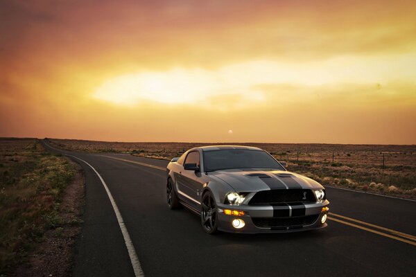 The car is eating on the road against the background of orange light