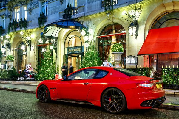 Maserati rojo en un edificio de lujo por la noche