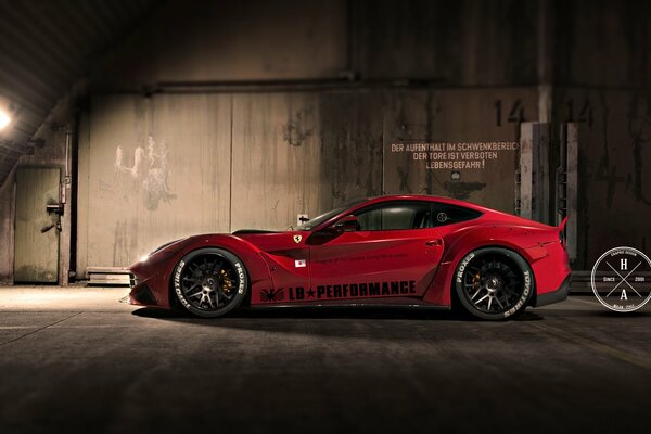 Czerwone stylowe Ferrari stoi w ciemnym hangarze