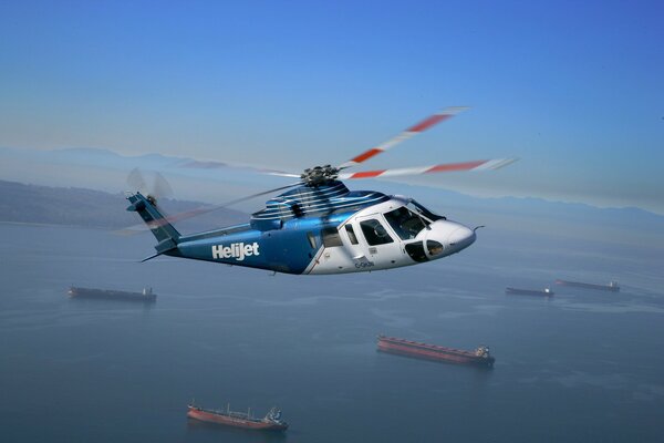 Helicóptero azul s - 76 en vuelo sobre el océano