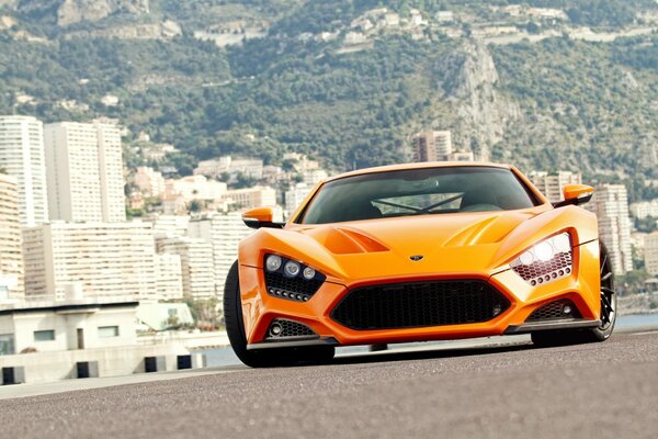 Supercar orange Zenvo sur fond de ville