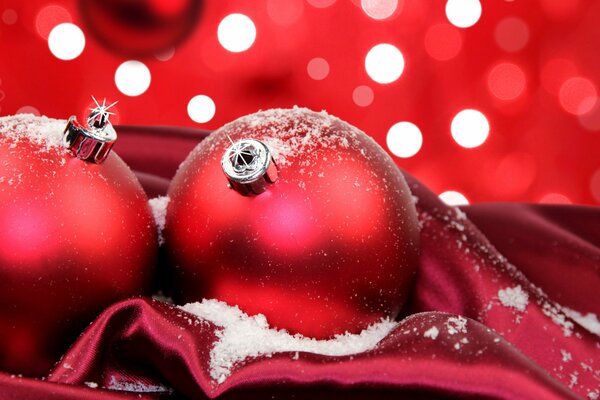 Palle di Natale rosse nella neve su tessuto rosso