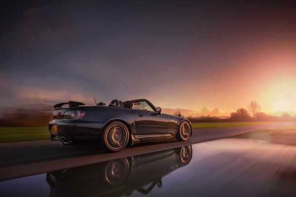 Hermoso coche que conduce al atardecer en la pista