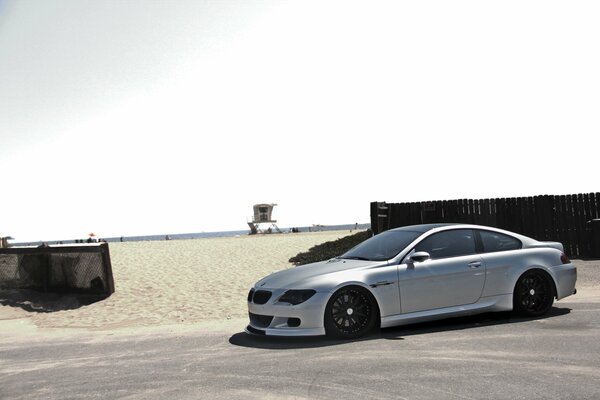 Silberner BMW m6 unter dem Himmel am Strand