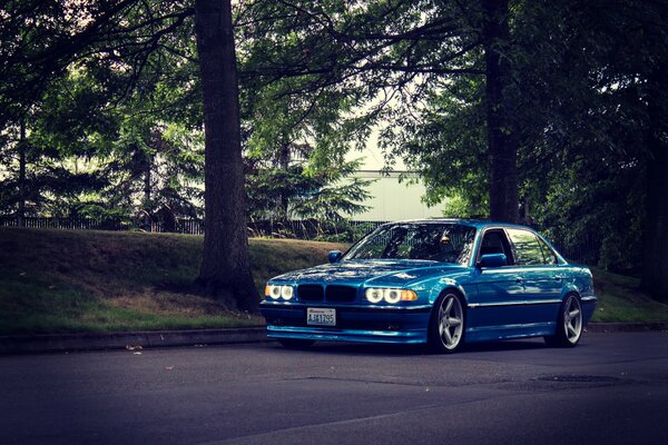 A tuned blue BMW is parked by the road