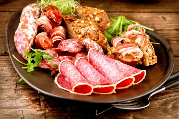 Slicing sausages and ham with bread on a plate