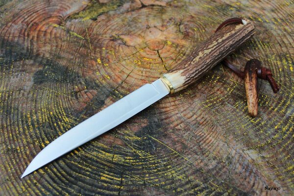 A long knife made of brass on a leather strap