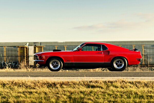 Un Ford Mustang rojo está parado en la carretera