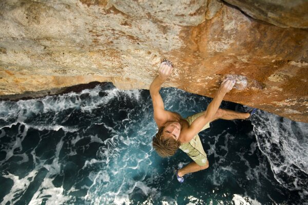 Guy extreme on a rock by the sea