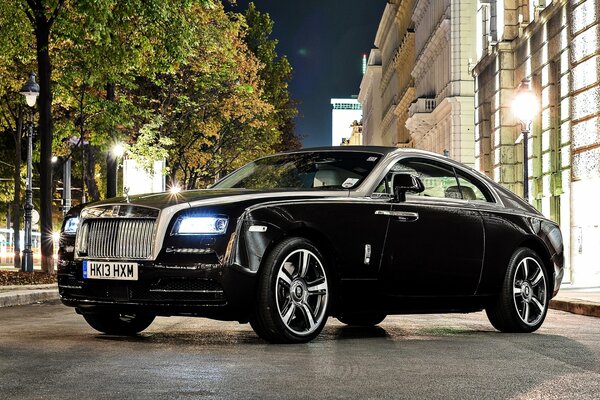 Rolls Royce de color negro en la calle nocturna de la ciudad