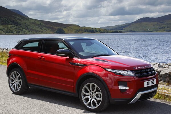 Voiture rouge Land Rover au bord du lac