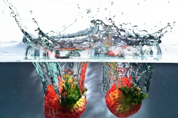 Erdbeeren fallen mit Spritzwasser ins Wasser