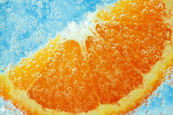 Plasterek pomarańczy pod wodą w bąbelkach