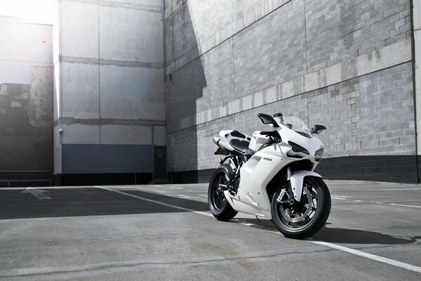 A beautiful gray motorcycle is standing next to the building