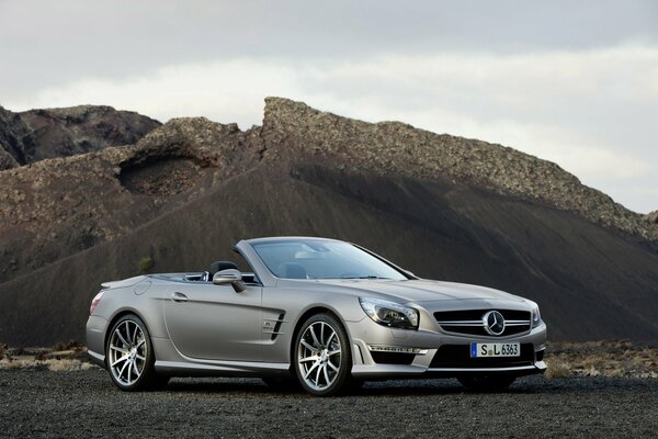 Der mercedes-benz sl 63 amg steht vor einem Hintergrund von Bergen und Wolken