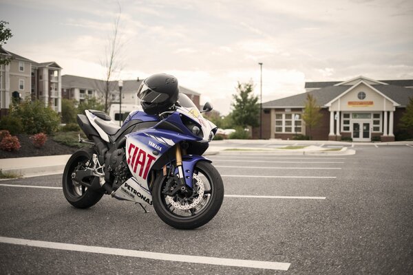 A blue Yamaha with a helmet is parked in an empty parking lot