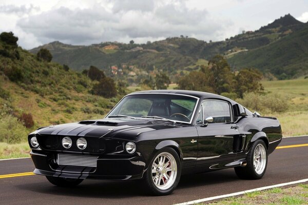 Ford Mustang nera sullo sfondo delle montagne