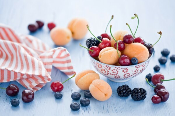 Berries and fruits in a cup are on the table