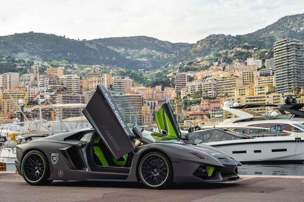 On the pier where the yachts are parked there is a gray Lamborghini