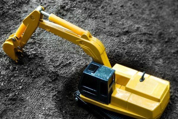 Escavatore giocattolo giallo nel terreno