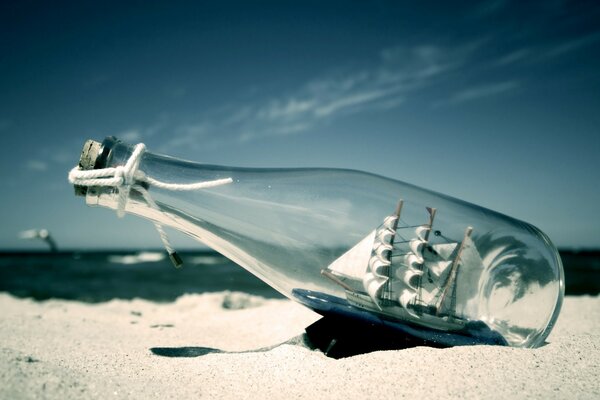 Foto de un velero dentro de una botella en la playa