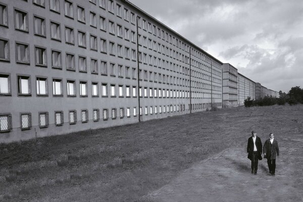 A long building with two people walking along it