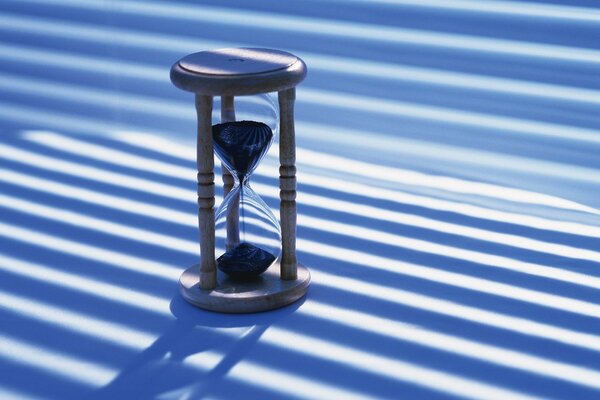 An hourglass stands on a striped background