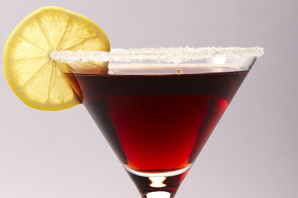 A glass with a red cocktail with salt, lemon on a white background