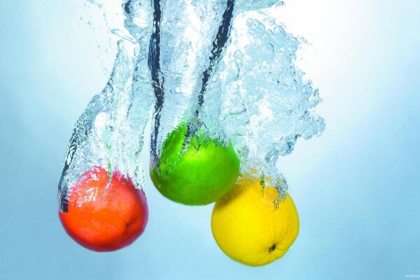Tres manzanas de colores se sumergen en el agua