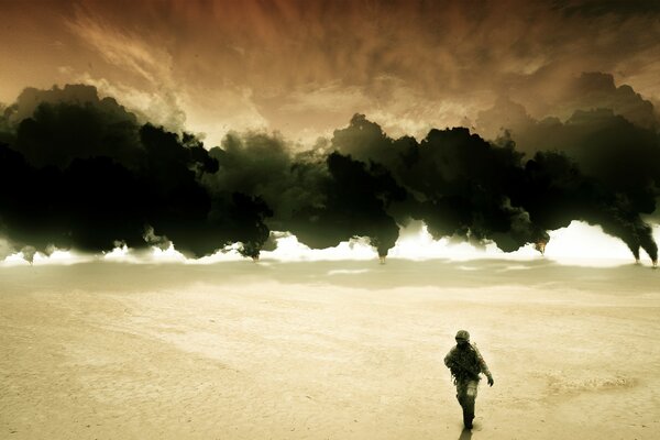 Un homme marche sur le sable sur fond de fumée noire