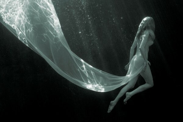Chica en las profundidades del agua en un vestido blanco