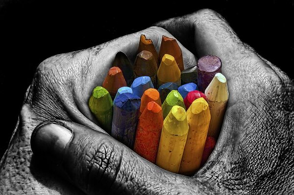 Les mains grises tiennent des crayons de couleur