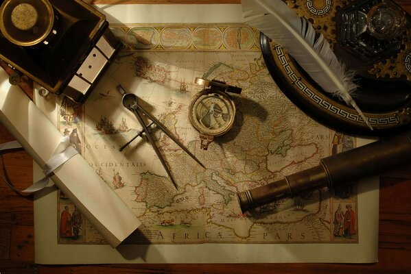 Подзорная труба, компас и перо лежат на карте