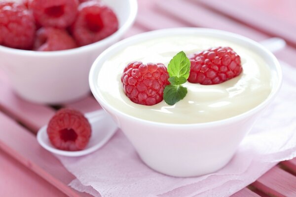 Milk dessert with raspberries in a white cup