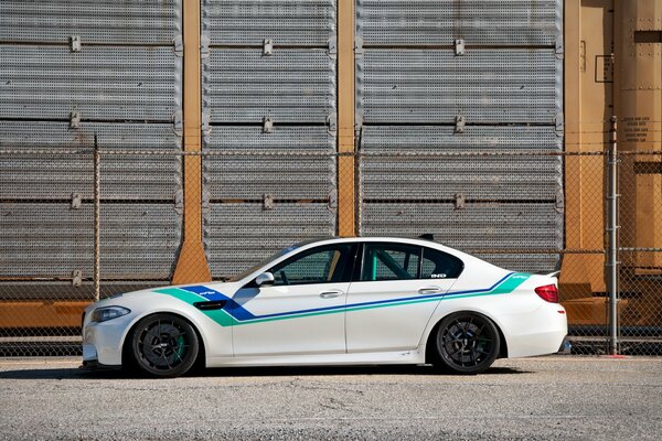 BMW M5 blanc avec des rayures multicolores, vue latérale