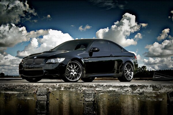 Black BMW car on the background of clouds