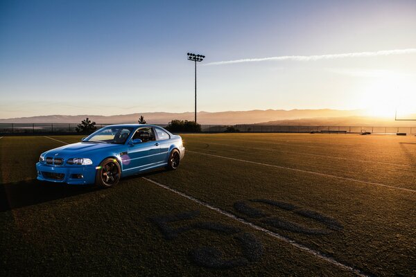 Blue racing BMW on the road at sunset