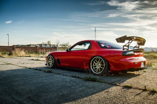 On old concrete slabs, a red sports Mazda with a rear spoiler