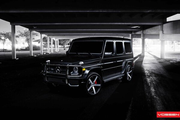 Mercedes Benz negro bajo el paso elevado en tonos oscuros