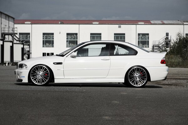 White tuned BMW on the side against the background of the building