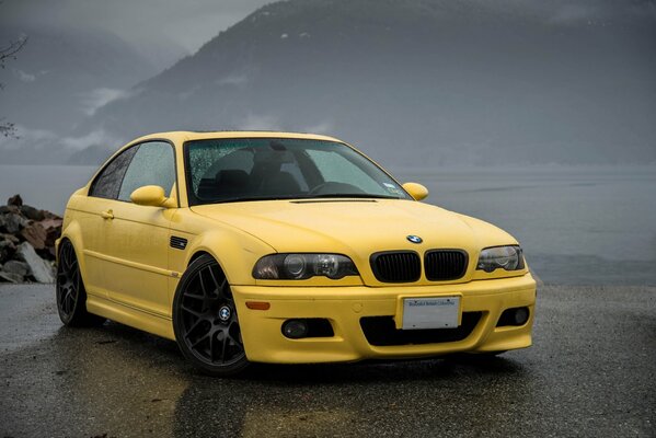 Coche deportivo BMW amarillo en asfalto mojado